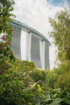 Iconic Marina Bay Sands hotel seen through vibrant tropical greenery in Singapore.