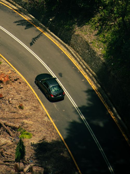 Free Aerial view of a car on a winding road through lush greenery in Kuala Lumpur, Malaysia. Stock Photo