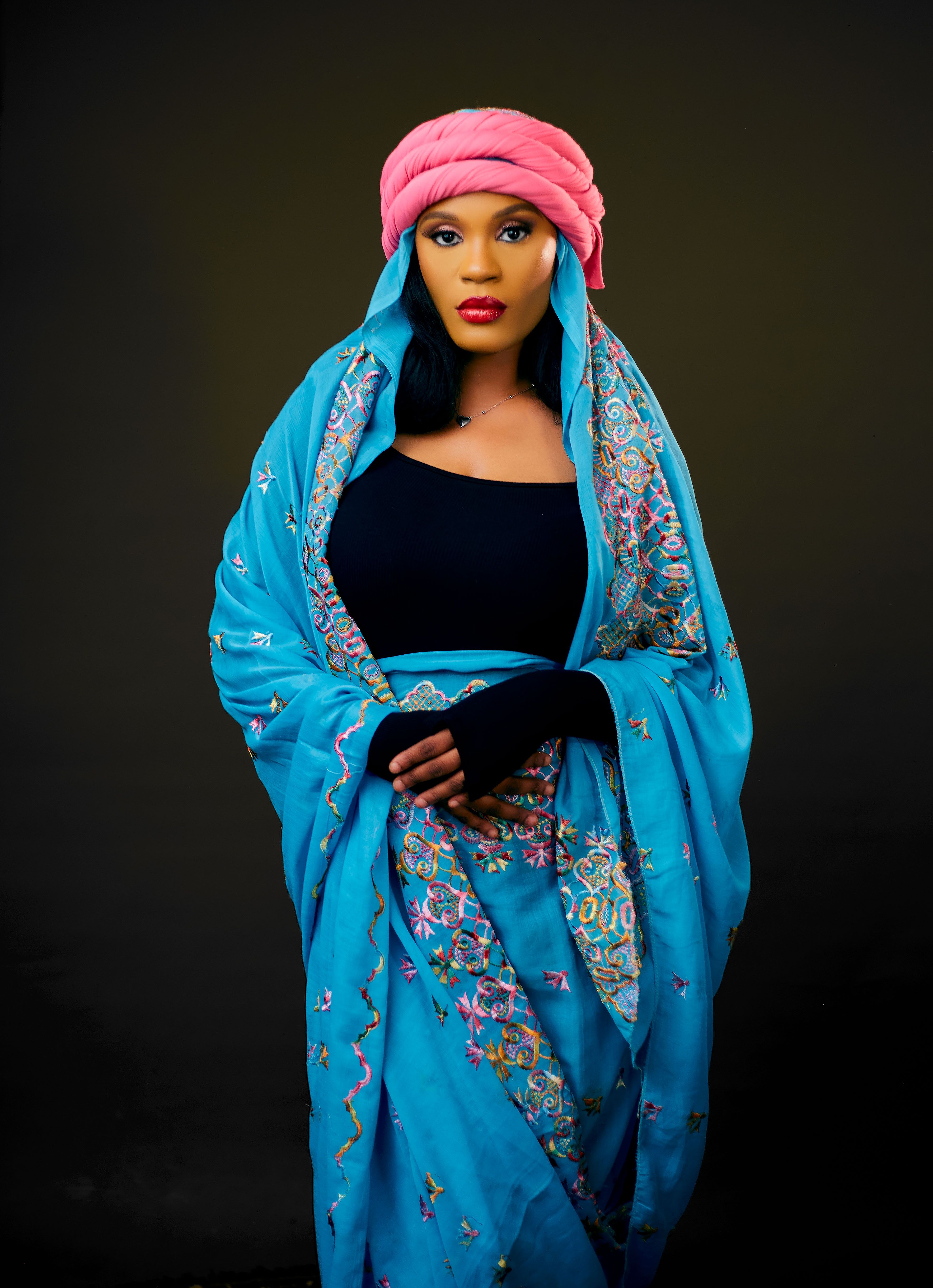Stylish portrait of a woman in vibrant blue and pink traditional clothing.
