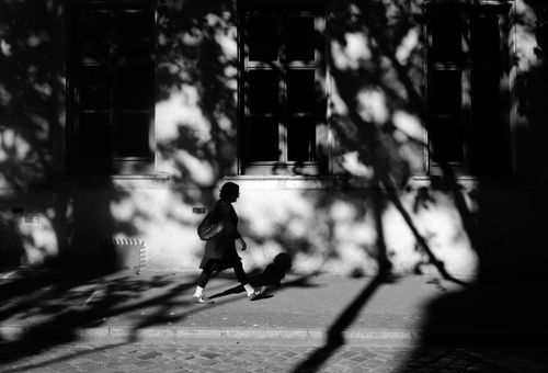Free Black and white silhouette of a person walking with dramatic shadows. Stock Photo