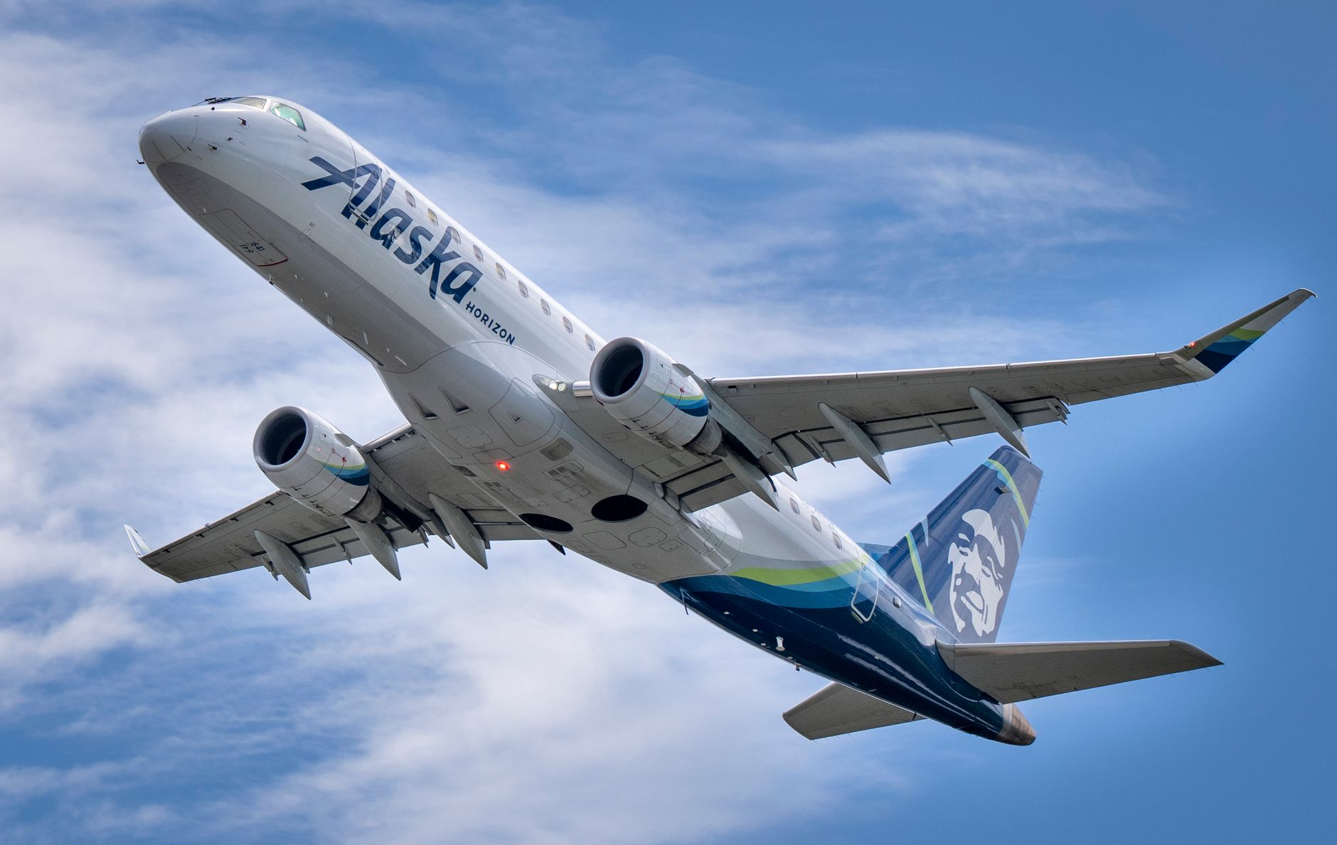 Photo by Alex Kovshovik A stunning capture of an Alaska Airlines jet taking off under a clear blue sky in Seattle, Washington.