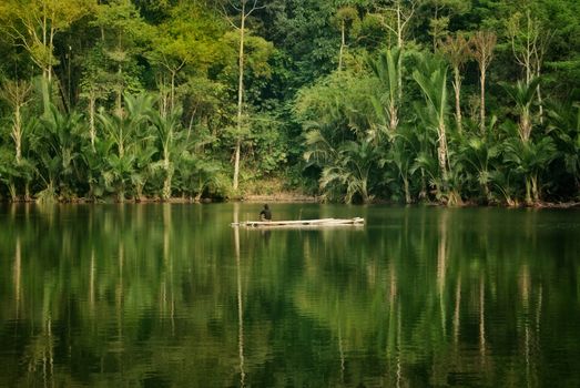 Serene view of a person on a raft in a lush green river landscape in Banten, Indonesia.