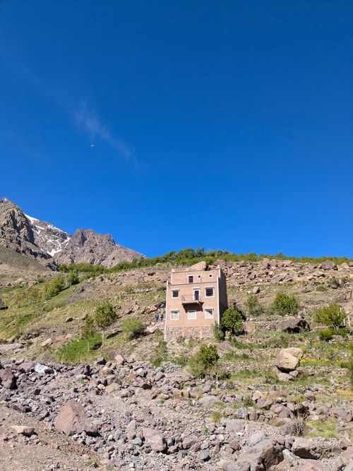 Free An isolated house stands prominently in Tachdirt, Morocco with rocky terrain and clear blue skies. Stock Photo