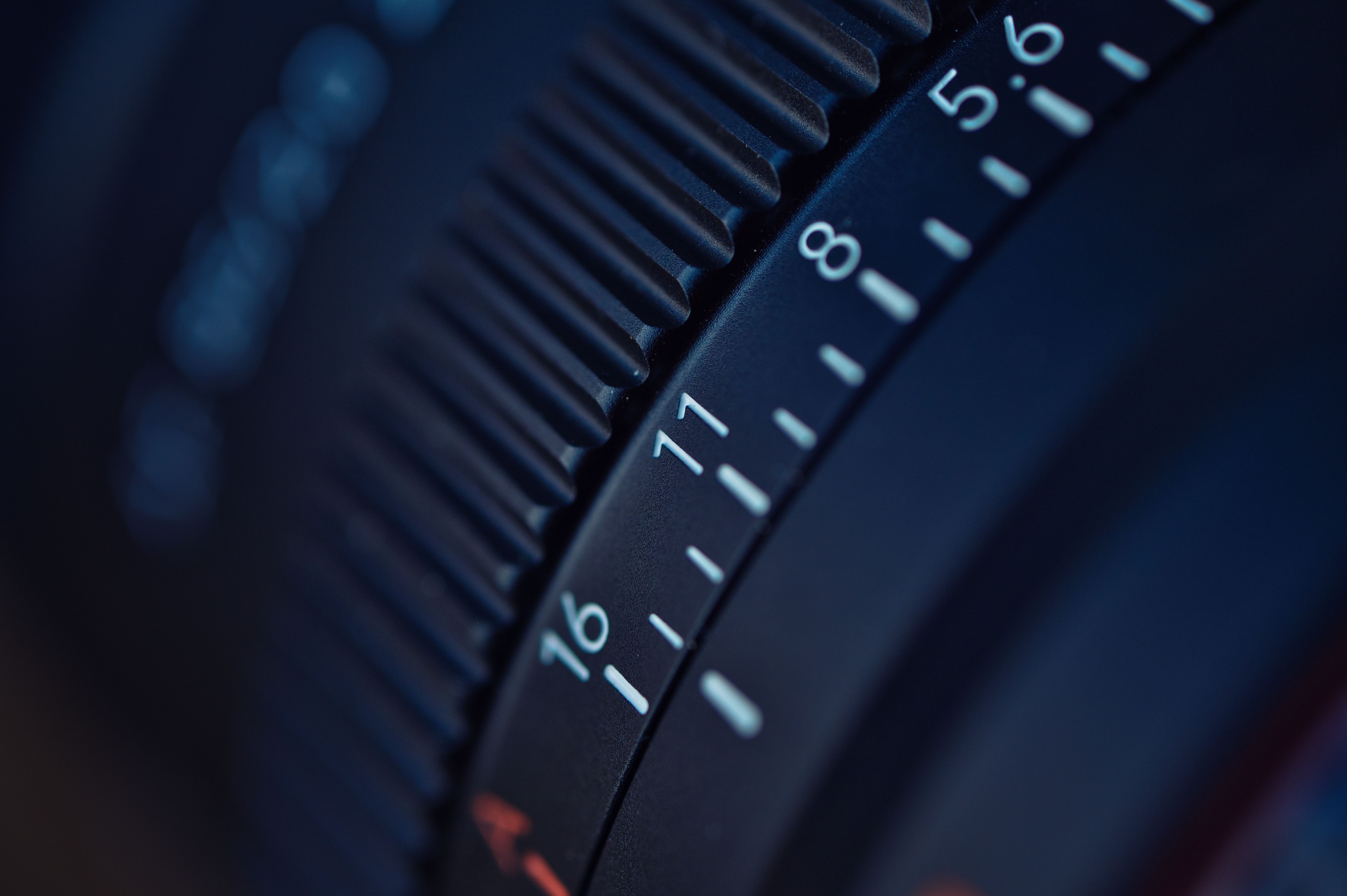 Detailed focus on a camera lens aperture ring, capturing f-stop numbers.