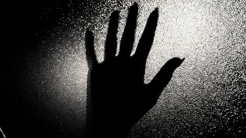 Free A silhouette of a hand pressed against textured glass creates a dramatic black and white effect. Stock Photo