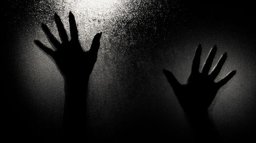 Free Dramatic silhouette of two hands pressed against a frosted glass, creating an eerie and mysterious ambiance. Stock Photo