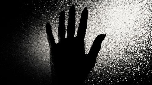 Free A dramatic silhouette of a hand pressed against a textured glass surface, creating a mysterious atmosphere. Stock Photo
