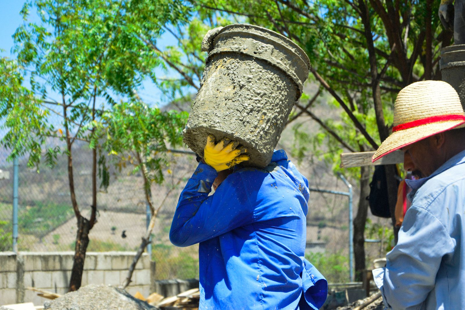 Construction worker carrying a bucket of heavy mixed material outdoors