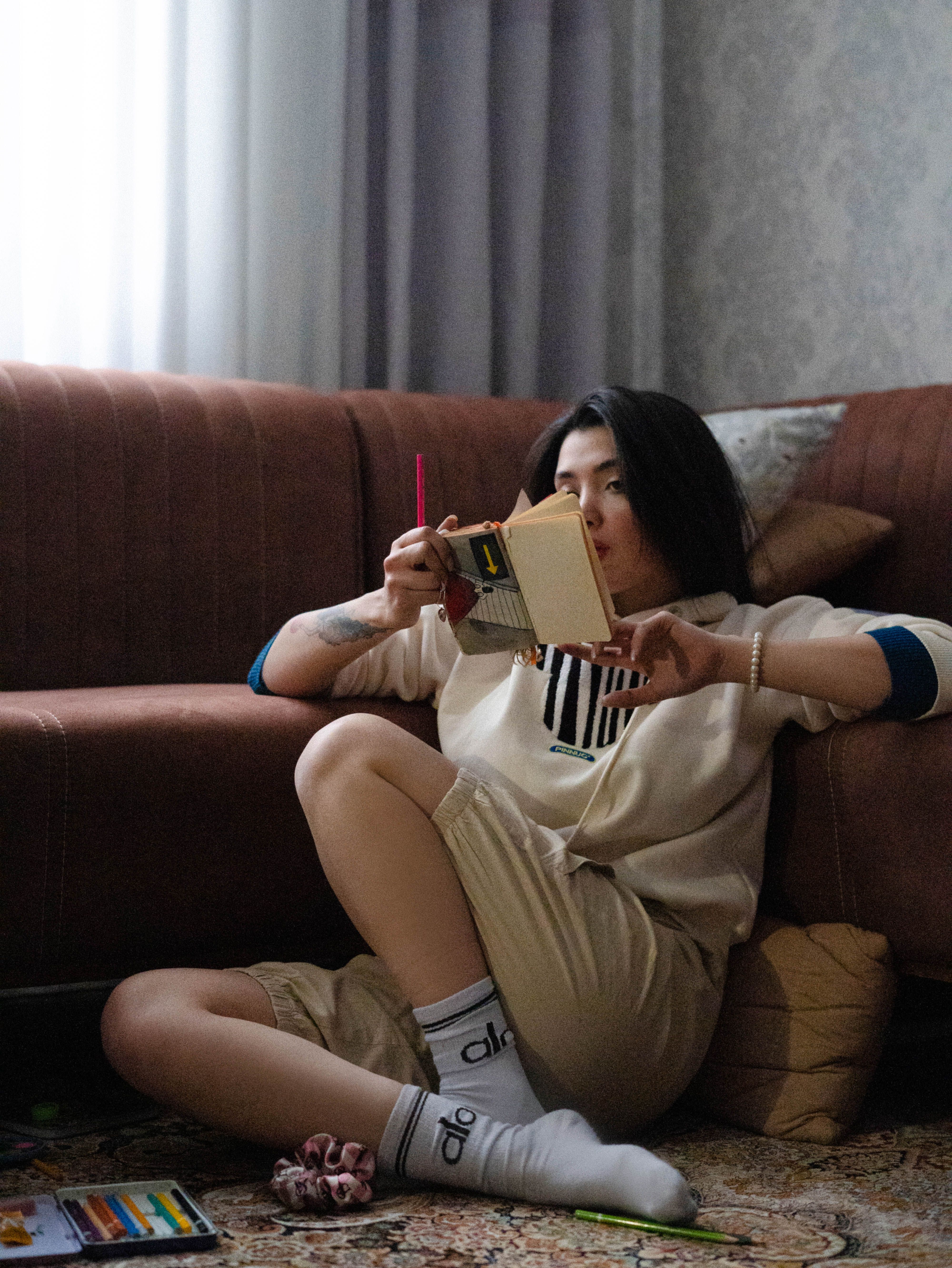 A young woman relaxes while reading a book indoors, creating a cozy atmosphere.