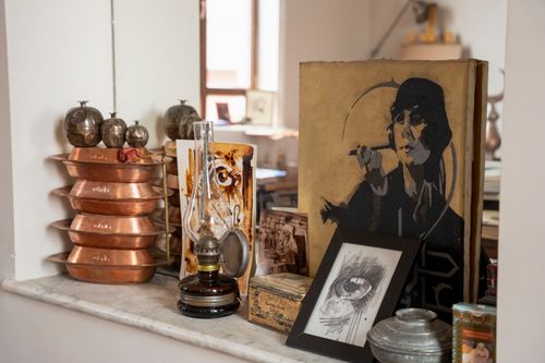 Free A collection of vintage home decor items including copperware, an antique oil lamp, and vintage art in a cozy indoor setting. Stock Photo