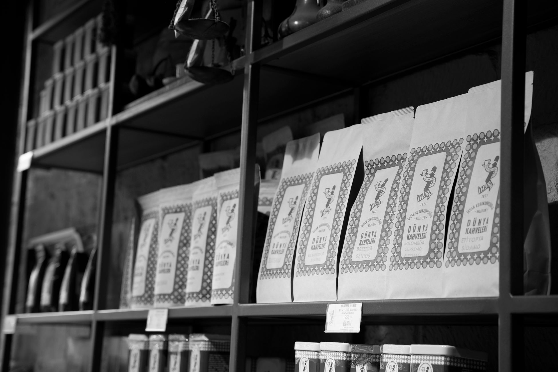 A monochrome image of coffee bags neatly arranged on a store shelf, creating an organized display.