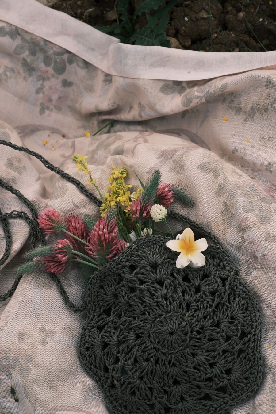 Delicate crochet piece with wildflowers on floral fabric