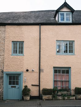 Quaint English cottage facade with pastel window frames, perfect for travel and lifestyle themes.
