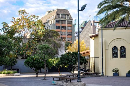 Free An urban view in Santiago, Chile, featuring trees, benches, and distinct architecture. Stock Photo