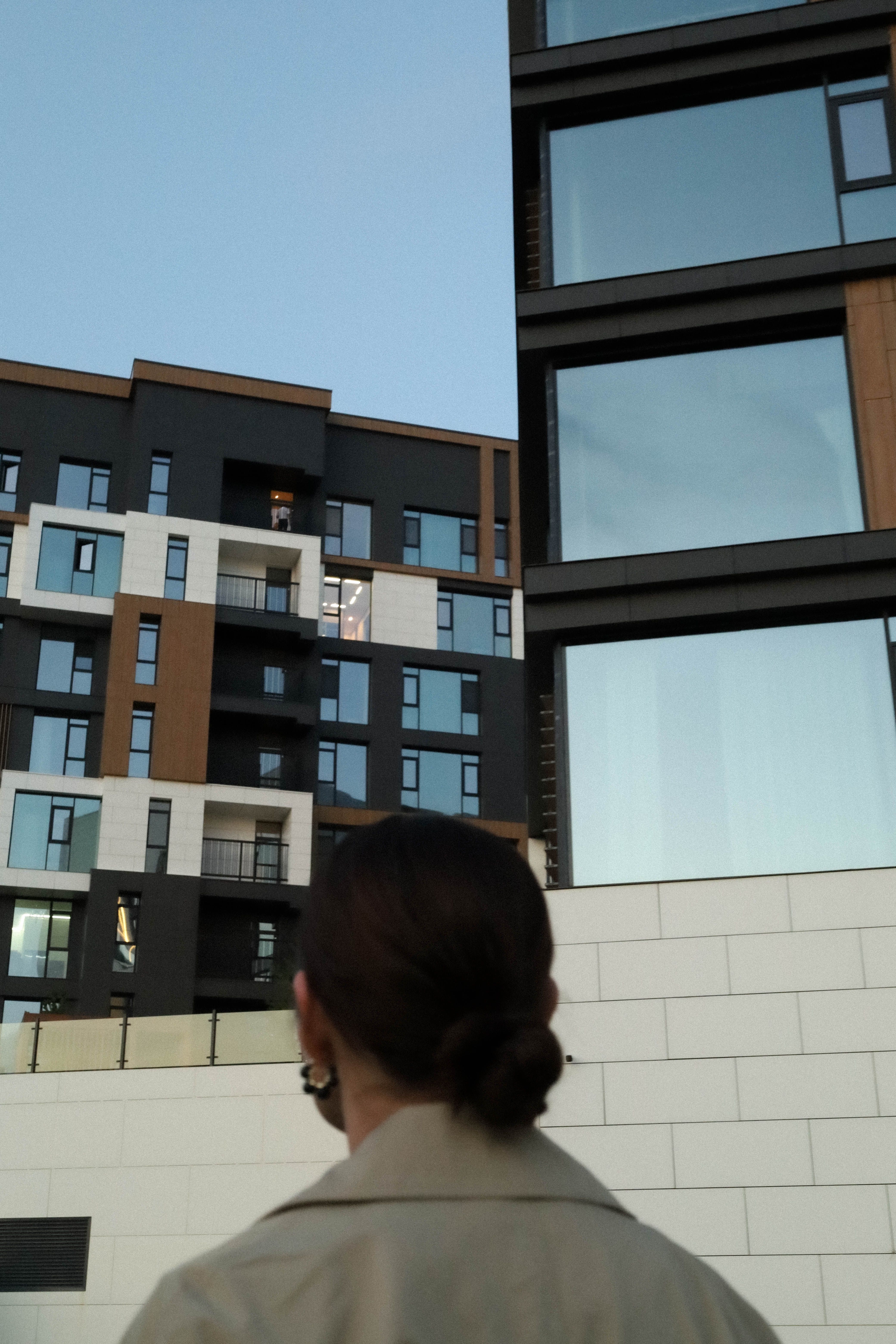 Person observing modern city architecture during early evening.
