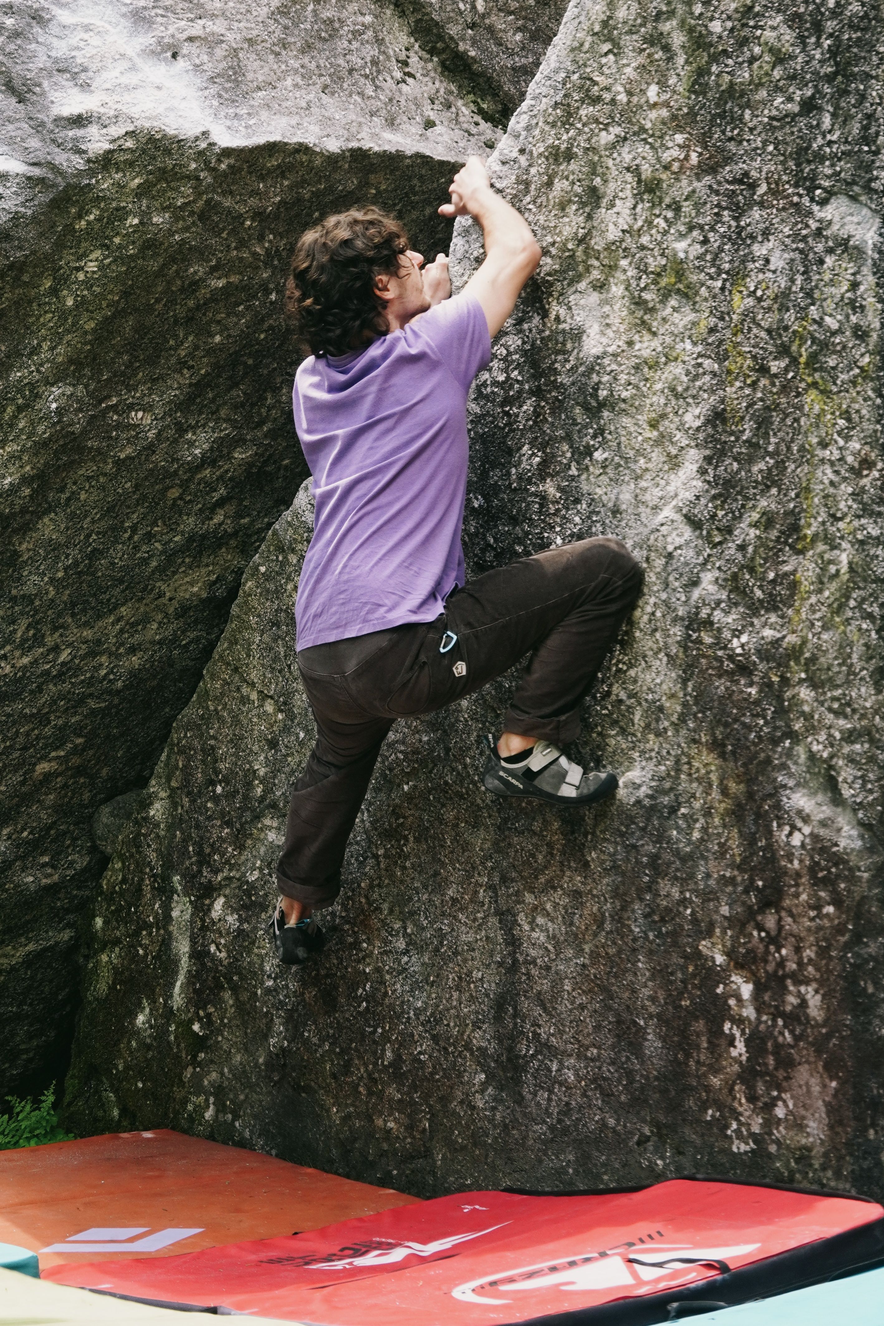 A man bouldering on a large rock in Lombardia, showcasing outdoor adventure.