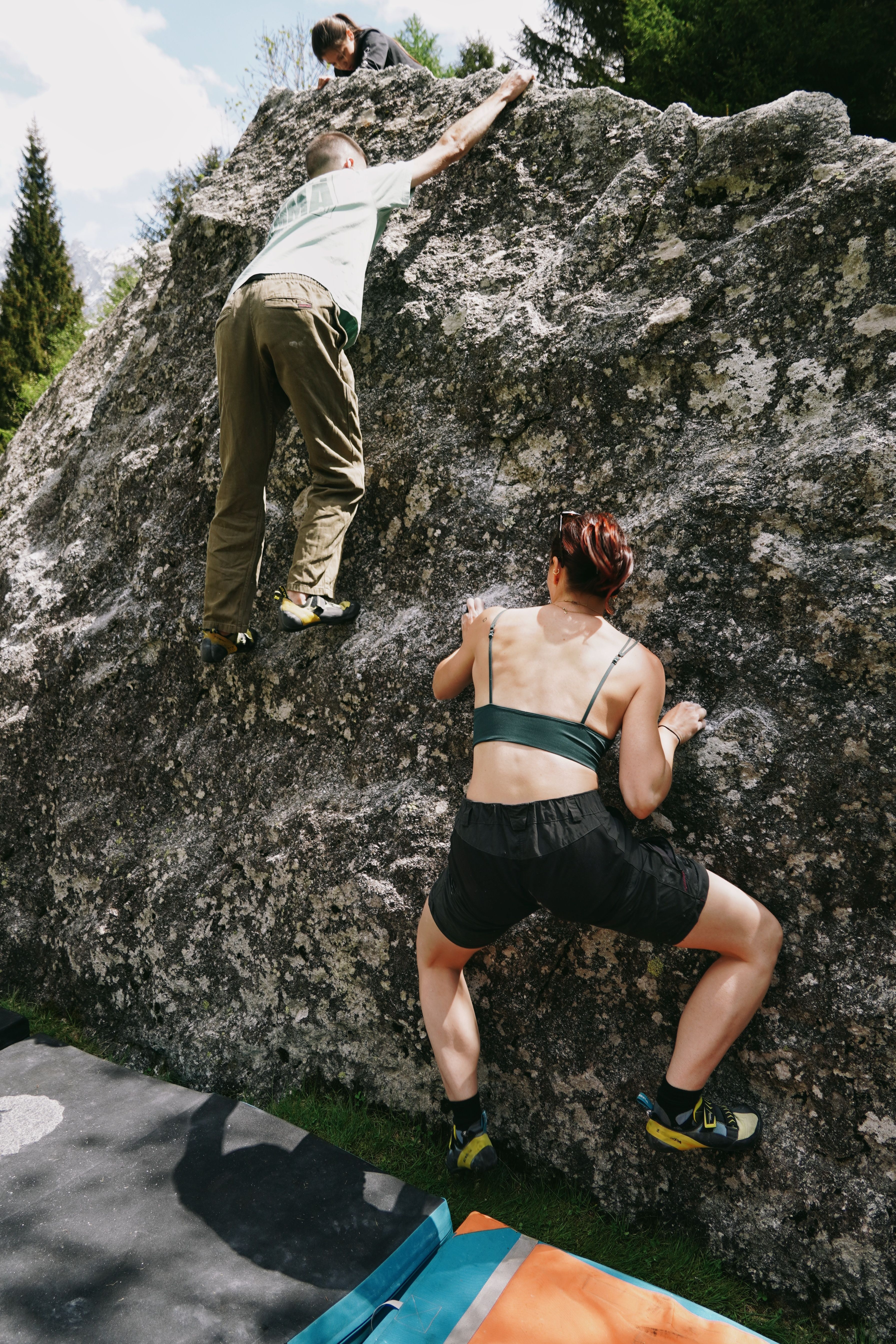 Group of climbers engaging in outdoor bouldering on a sunny day in Lombardia, Italy.