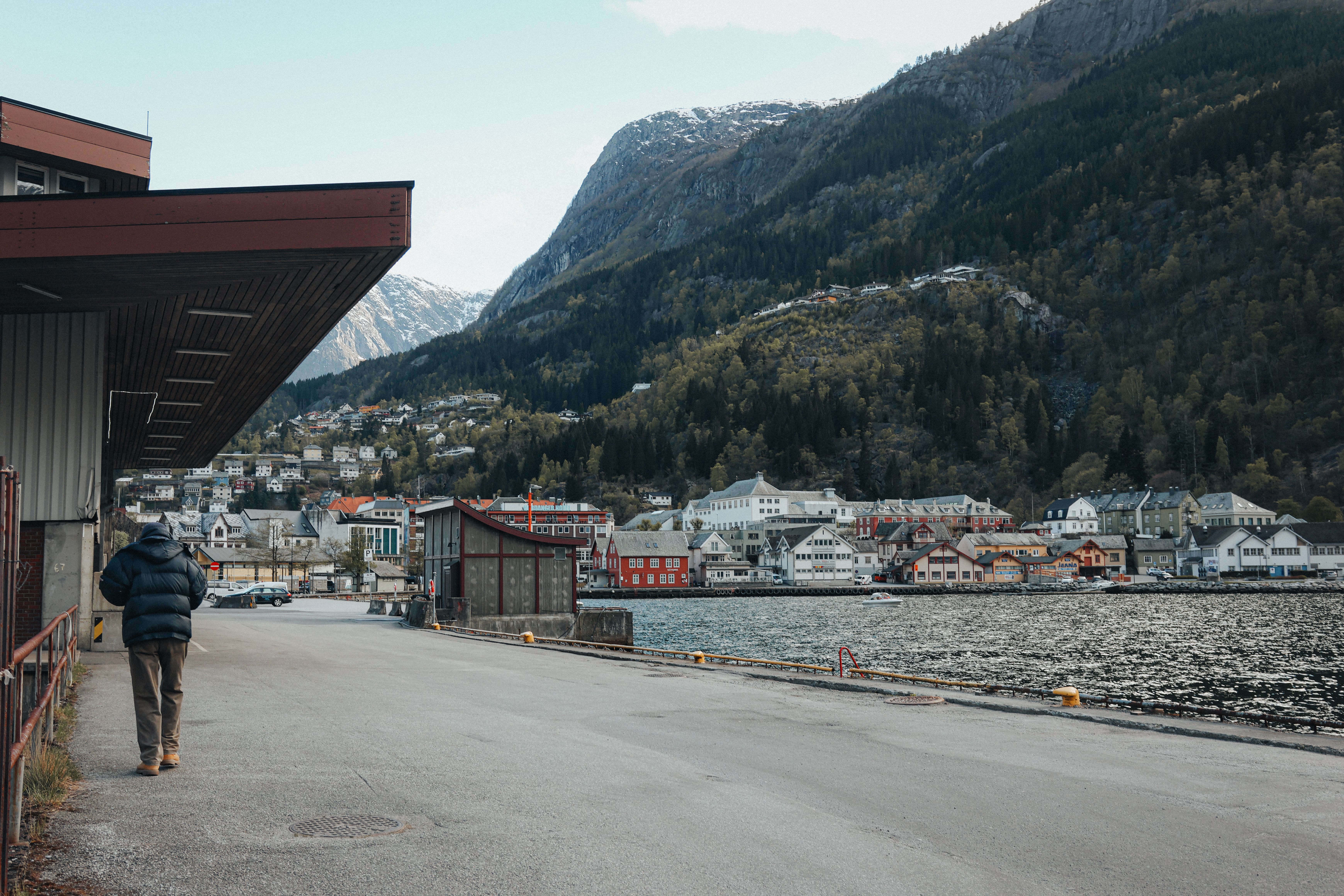 Picturesque dockside view in Odda, Norway, with majestic mountains and quaint townhouses.