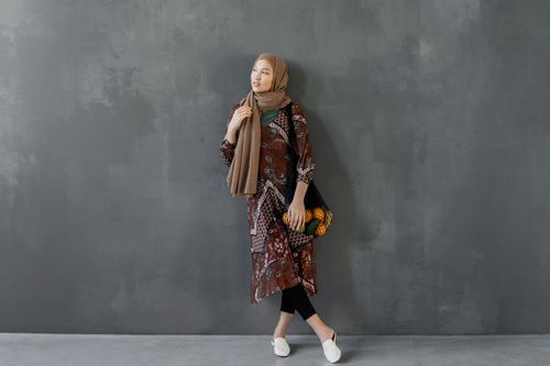 Free Stylish woman in a hijab posing against a textured wall, showcasing traditional wear. Stock Photo