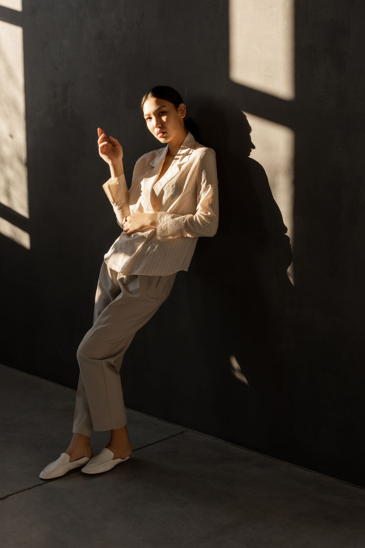 A woman leaning on a wall in a relaxed editorial pose