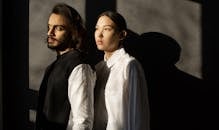 一对时尚前卫的夫妇靠墙站着，在日光下投出戏剧性的阴影