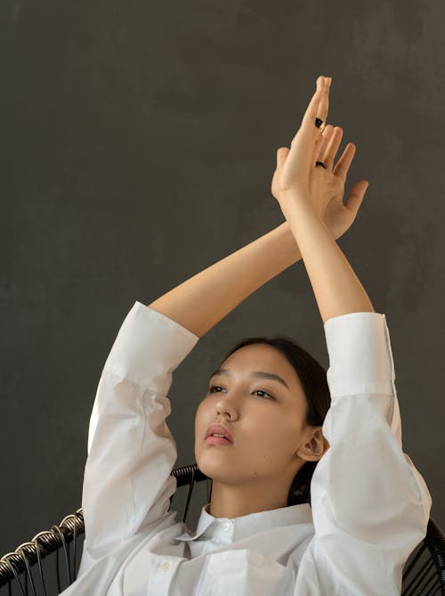 Woman in White Long Sleeve Shirt Raising Her Hands