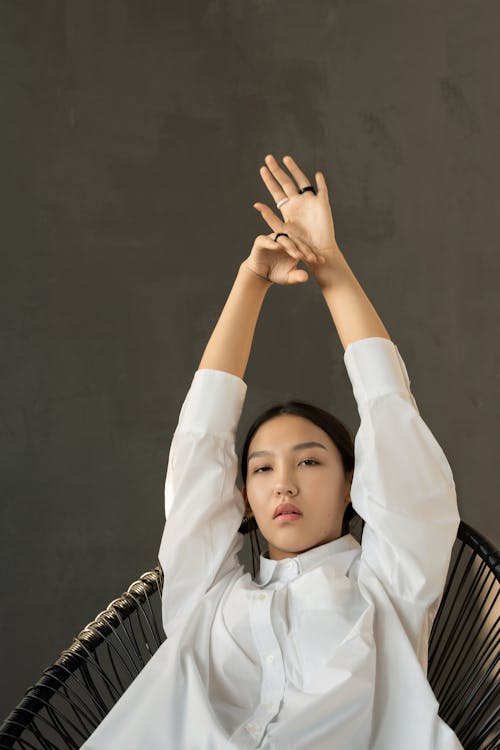 Woman in White Long Sleeve Shirt Raising Her Right Hand