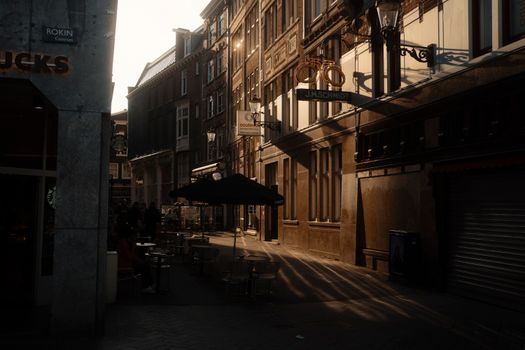 Golden sunlight casts long shadows on a European street lined with classical architecture.