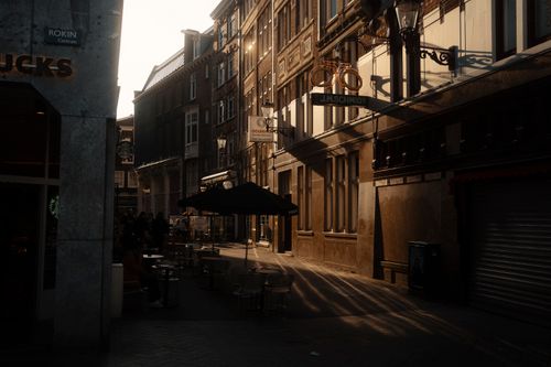 Free Golden sunlight casts long shadows on a European street lined with classical architecture. Stock Photo