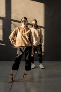 Trendy couple showcasing minimalist style in natural sunlight indoors.