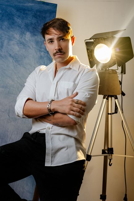 Confident man in a studio setting with professional lighting equipment, ideal for photography and portrait content.