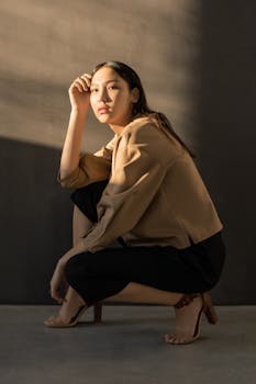 一位白人女性摆出优雅的姿势，身着时尚服装，在柔和的工作室灯光下显得格外突出