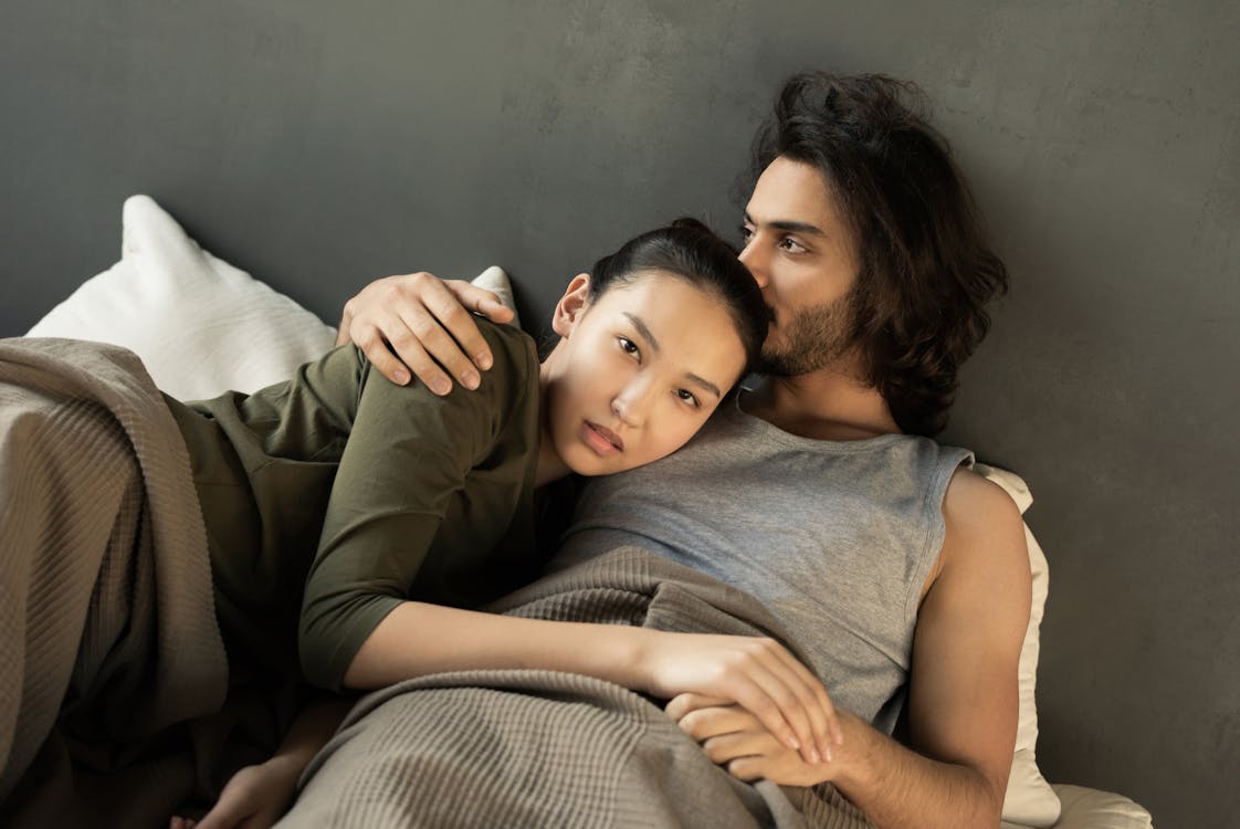 Free Woman in Green Top Lying on a Man's Chest in Bed Stock Photo