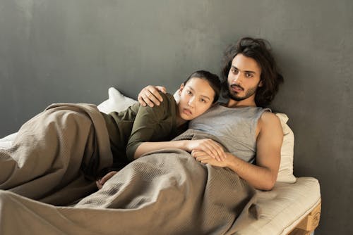 Free Woman in Gray Tank Top Lying on Bed Beside Girl in White Shirt Stock Photo