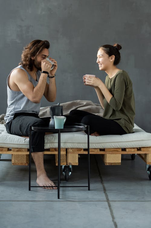 Free Man and Woman Sitting on a Bed Having Breakfast Stock Photo