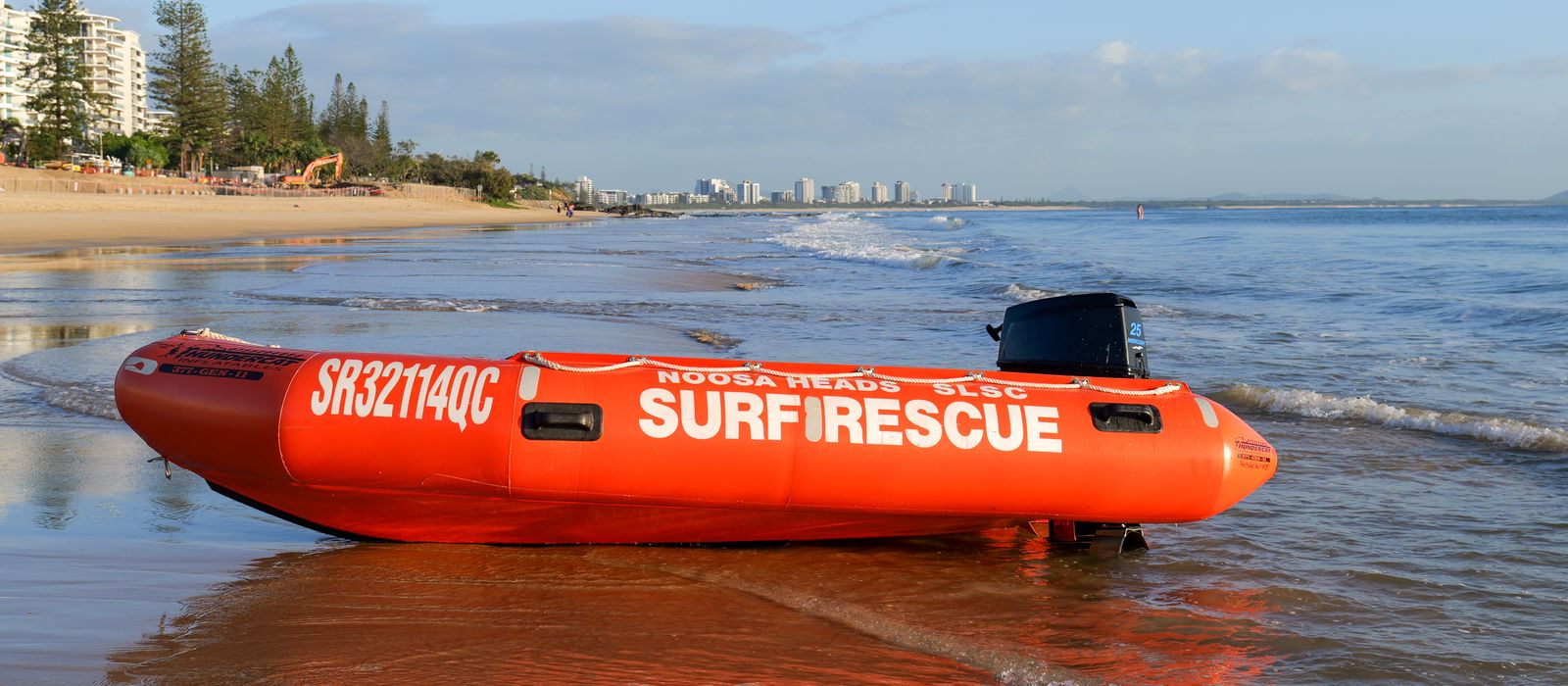 A bright orange surf rescue boat on Mooloolaba Beach, Queensland during sunrise.