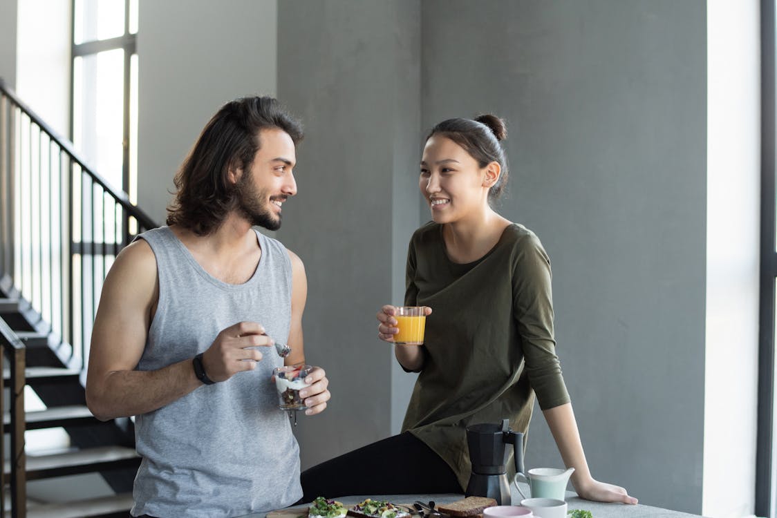 Free Man in Grey Tank Top and Woman in Green Top Holding Clear Drinking Glass Stock Photo