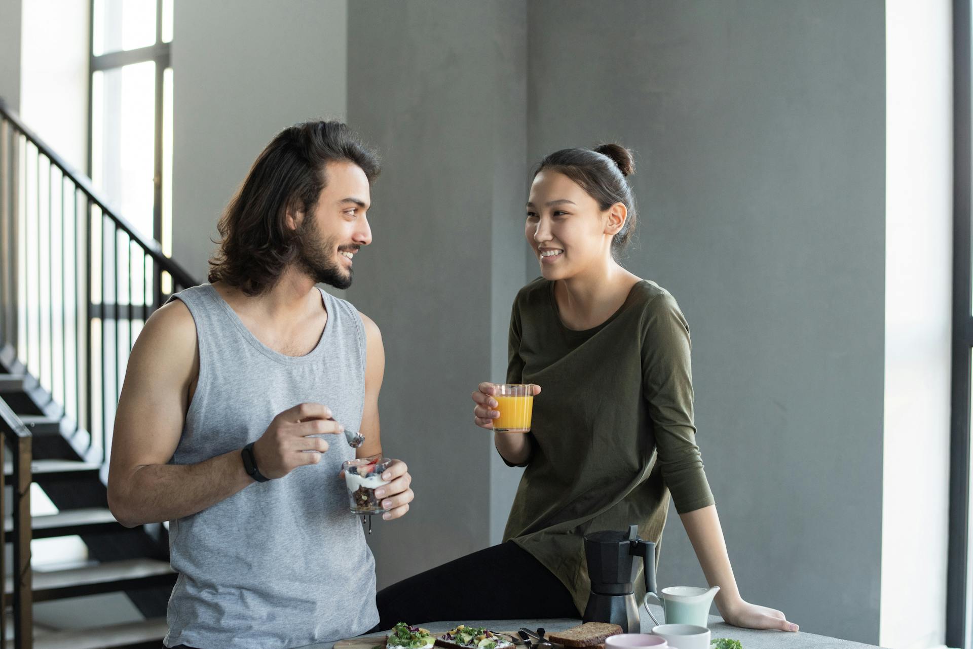 A happy young couple sharing a breakfast moment with juice and snacks indoors.