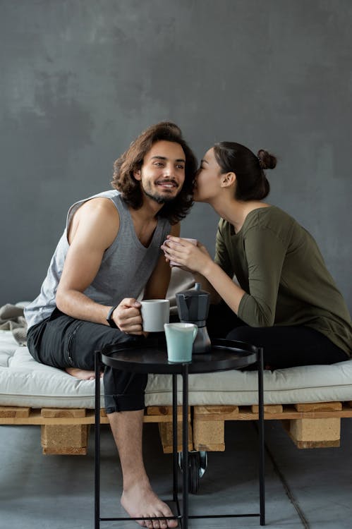 Free Woman in Green Top Whispering to a Man in a Gray Tank Top Stock Photo