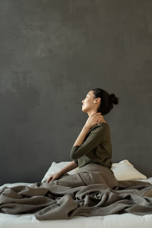 Woman in Gray Dress Sitting on Bed