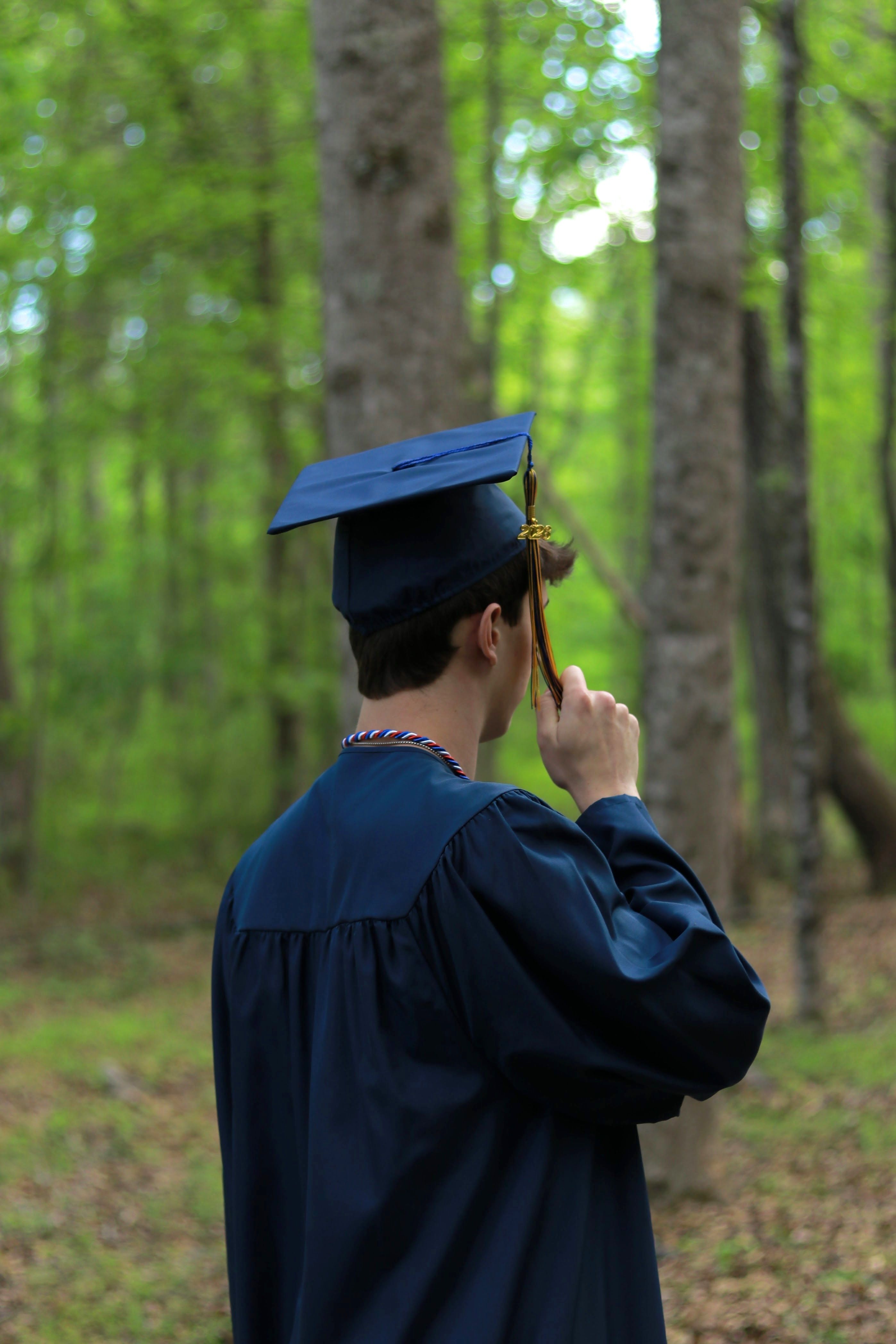 Graduation in Blue Cap and Gown Amidst Forest · Free Stock Photo
