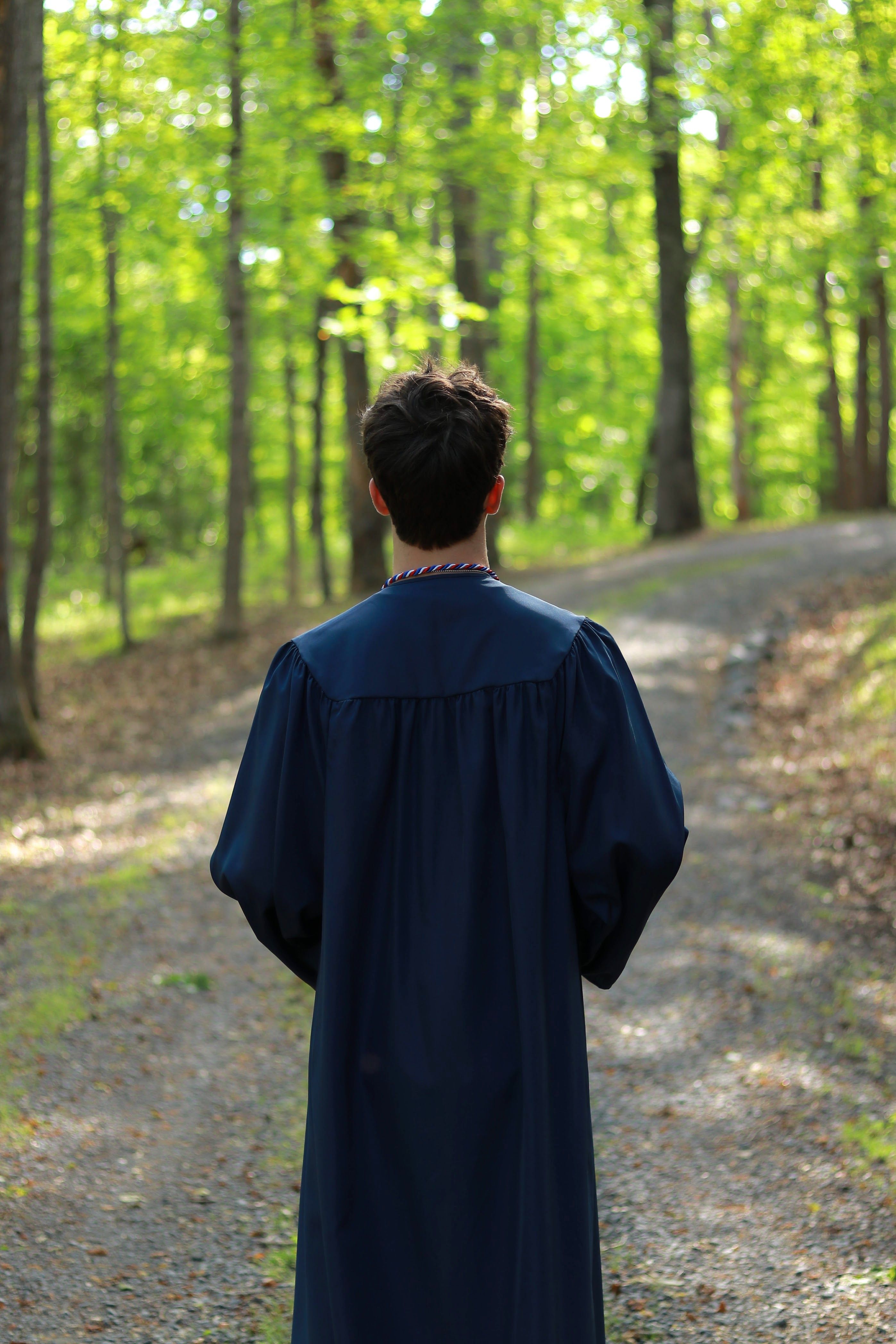 Young Graduate Walking Through a Forest Path · Free Stock Photo