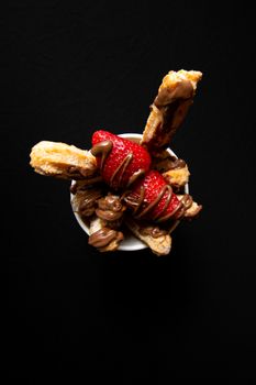 Churros covered in chocolate and strawberries, creating a delightful dessert treat.