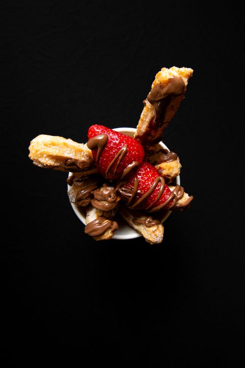Free Churros covered in chocolate and strawberries, creating a delightful dessert treat. Stock Photo