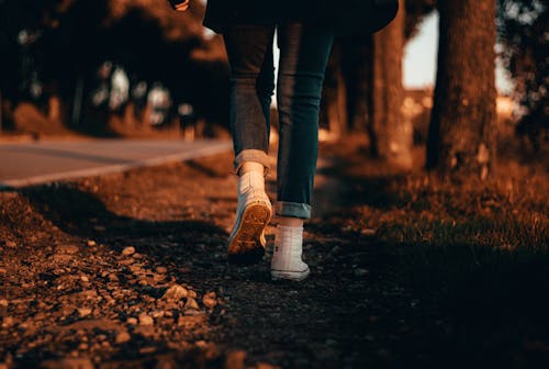 Person in Blue Jeans and White Sneakers Walking on the Ground