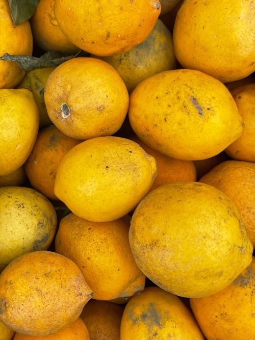 Free A vibrant close-up of fresh lemons stacked outdoors, showcasing their bright yellow hue. Stock Photo
