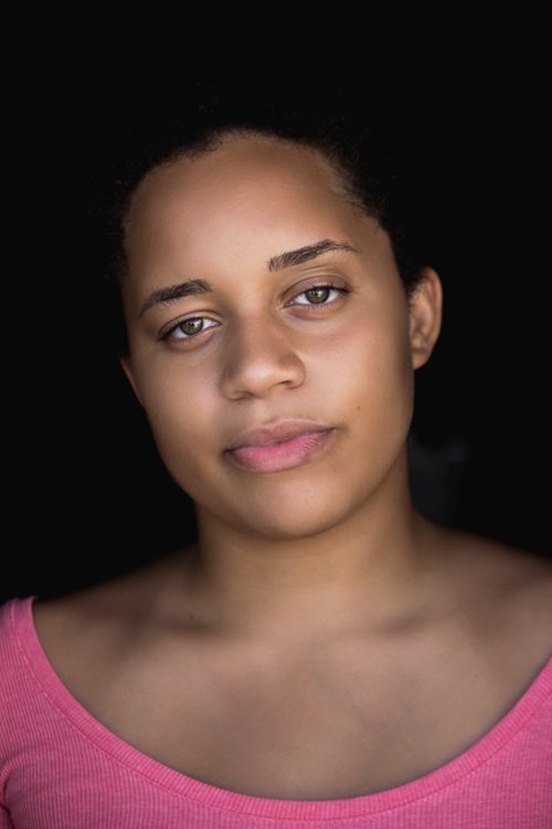 Free Close-up portrait of a young woman in a pink top with a neutral expression. Stock Photo
