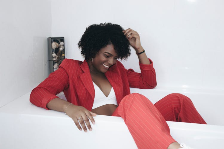 Photo Of Laughing Woman In Red Pinstripe Suit Sitting Inside Bathtub