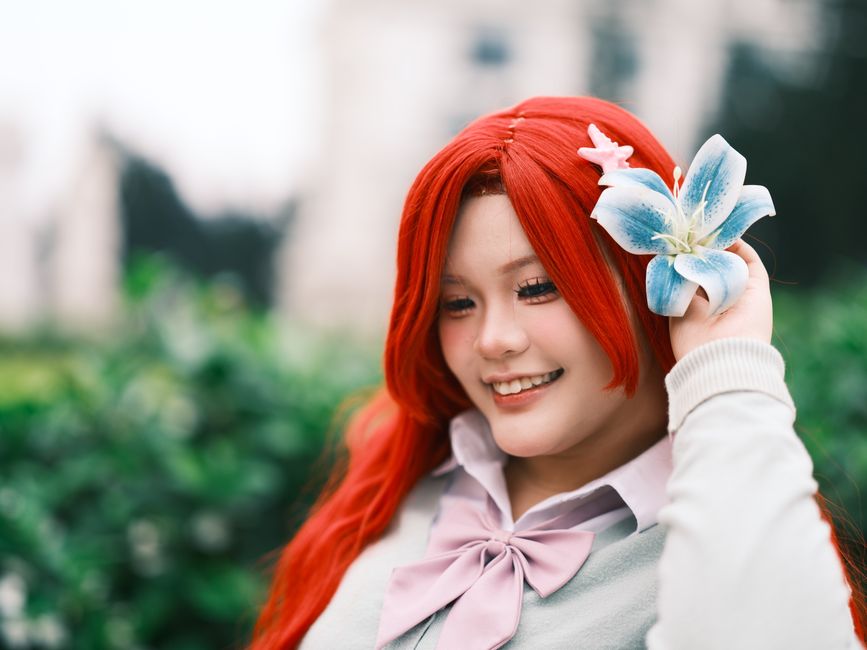 A joyful woman in vibrant cosplay attire poses outside, showcasing a playful atmosphere in a lush Vietnamese garden.