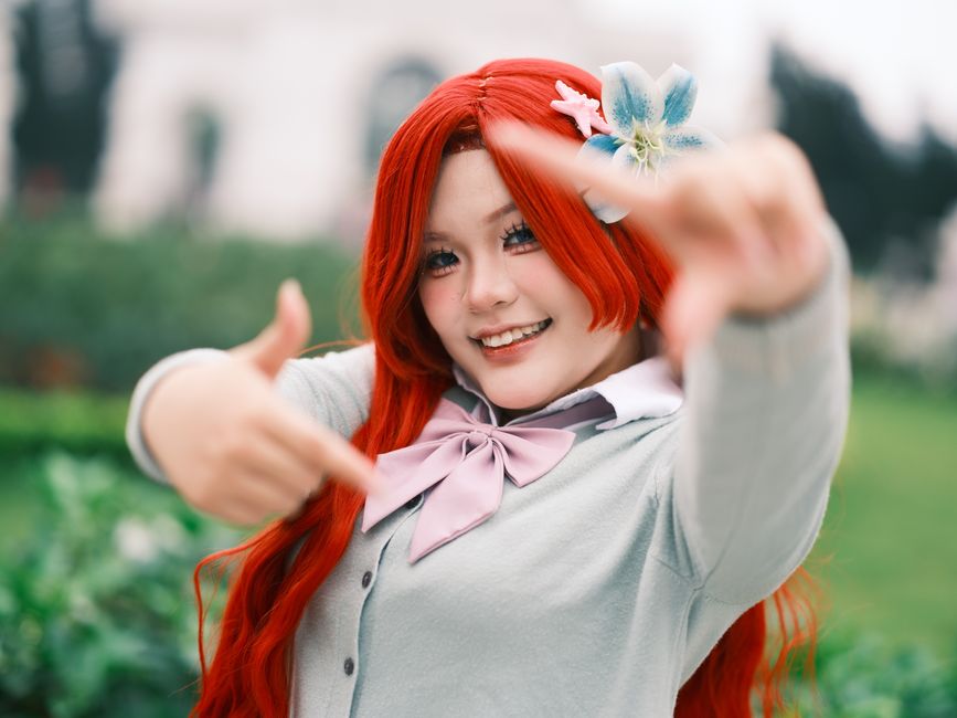 Capture of a young woman in colorful cosplay with vivid hair and accessories outdoors in Vietnam.